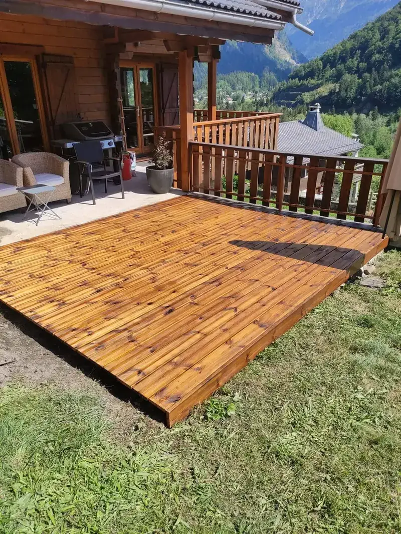 Terrasse en bois saturée devant un chalet de la vallée de l’Arve, réalisée par Défi Bois
